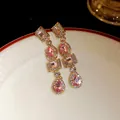 Primo piano di orecchini vintage geometrici con cristalli rosa e finitura dorata - Rosa / Oro