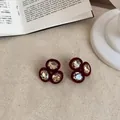 Vue détaillée de boucles d'oreilles floquées bordeaux vintage avec des cristaux brillants - Rouge/Café