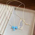 Gros plan détaillé d'un pendentif cheval en émail bleu sur un collier cordon crème - Collier / Bleu