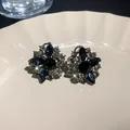Close-up detail of vintage floral stud earrings featuring blue and clear crystal rhinestones - Floral Shape (HE11163) / Gray