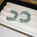 Handcrafted blue natural stone beaded hoop earrings with gold accents on white velvet tray - Gold Beaded Silver Post Style / Blue