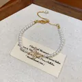 Primo piano di un bracciale di perle vintage francese con ciondolo a farfalla lucente. - Stile Pendente Farfalla con Strass (6#) / Oro