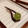 Close-up of minimalist brown hair clip with large round green resin sphere on velvet - Duckbill Hair Clips / Green