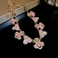Close-up detail of vintage French necklace featuring pink cat's eye gems and crystal flowers - Bronze-Pink-Coffee