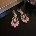 Close-up of vintage palatial style earrings with pink water-drop stones and rhinestones - Bronze-Green-Pink