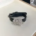Detailed view showing the sparkling rhinestone rose decoration on a black leather strap bracelet. - Flower Bracelet / Black
