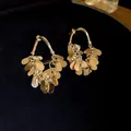Vue détaillée de créoles dorées avec d'élégants pétales pailletés en cascade et tiges en argent. - Style à Gland de Paillettes / Or