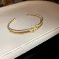 Close-up of elegant double-layered gold bangle with zircon-encrusted flower detail - Gold