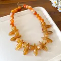 Detailed close-up of an amber acrylic marbled necklace featuring irregular oval beads. - Amber Marbled