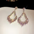 Close-up of sparkling pink zircon teardrop dangle earrings presented on a minimalist white tray - Hollow Teardrop