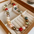 Detailed close-up view of a multi-colored pearl necklace inside a vintage wooden box. - 12mm Bead Diameter / Colorful
