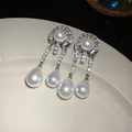 Primo piano di orecchini pendenti vintage eleganti con diamanti e perle a goccia. - Stile a Goccia di Corte Vintage / Argento