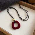 Close-up detail of vintage burgundy flocked ring pendant with gold bead jewelry - Hollow Ring Necklace