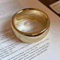 Close-up view of minimalist high-polish gold wide band ring on vintage book page. - Thick Rounded Style (3)