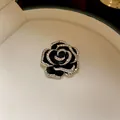 Elegante spilla a camelia nera con bordi in zircone, mostrata in confezione di lusso. - Stile Camelia Nera (Spilla) / Nero