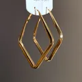 Vista macro dei dettagli degli eleganti orecchini a cerchio geometrici a rombo dorati - Grande / Oro