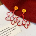 Close-up of red horse-shaped earrings with yellow Fu character studs on red fabric - 3# Red