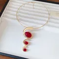 Detail view of a gold-toned necklace with red resin oval stones on a jewelry tray - Choker Necklace / Gold-Red