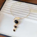 Detailansicht einer goldenen Halskette mit ovalen Anhängern aus schwarzem Harz - Choker-Halskette / Gold-Schwarz
