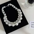 Close-up of a vintage pearl necklace with rhinestones on a black velvet display. - Necklace / Silver-White