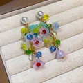 Close-up of colorful resin flower tassel earrings with pearl studs on a jewelry tray. - Tassel Flower Style / Colorful