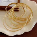 Close-up of elegant multi-layered gold metal bangles with textured finish - Multi-layer Hoop Style / Gold