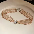 Detail of brown lace choker with star rhinestone pendant on white ceramic plate - Star / Silver-Gold-Brown