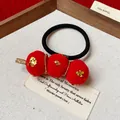 Primer plano de un coletero tanghulu con pompones rojos, estrellas y purpurina dorada - 49# Goma de pelo / Rojo