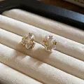 Close-up of elegant gold star stud earrings with pearl finish and sparkling zircons - Silver Needle / Gold