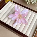 Gros plan détaillé d'une pince à cheveux en forme de lys rose en soie dans une boîte à bijoux - Pince à Bec de Canard Fleur de Lys / Rose Clair