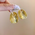 Nahaufnahme von goldfarbenen, gehämmerten, unregelmäßigen Ohrsteckern mit Textur - Gold