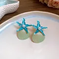 Detailed view of ocean-themed blue starfish and seashell stud earrings with central pearls - Blue Green