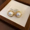 Primer plano de pendientes vintage dorados con grandes perlas de imitación centrales. - Estilo Redondo Retorcido Blanco / Dorado