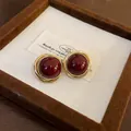 Vista detallada de pendientes vintage dorados con perlas rojo oscuro en un estuche - Estilo Redondo Retorcido Rojo / Dorado