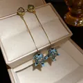 Böhmische Quastenohrringe mit blauen Emaille-Blumenanhängern und funkelnden Straßsteinen. - Stil 48# / Silbernadel / Gold-Blau