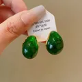 Detail view of translucent green water drop earrings with gold trim on a display card - Green