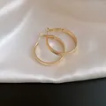 Close-up of golden textured hoop earrings with a pleated pattern on white silk - Diameter 30MM / Gold