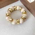 Vista dettagliata di perle acriliche marmorizzate e distanziatori dorati irregolari. - Bead Splicing (HB4541) / Bianco