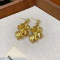 Macro view of elegant gold-toned wrinkled leaf earrings with sparkling crystal studs - Gold