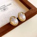 Close-up of French vintage irregular gold earrings with pearlescent faux pearl detail - Gold - Style B