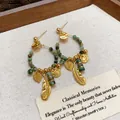 Primo piano di orecchini a cerchio placcati oro con perline turchesi e piume - Orecchini a lobo / Oro Verde Scuro
