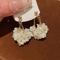 Détail rapproché de boucles d'oreilles vintage à pampilles de fleurs blanches nacrées et or - Or
