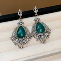 Detail view of vintage-style teardrop earrings featuring green stones and sparkling rhinestones. - Silver Earring Post - Gold - Green