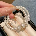 Detailed view of oversized gold hoop earrings featuring graduated white lustrous faux pearls. - Silver Earring Post Style / White