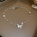Close-up of silver butterfly pendant and pearls on a transparent necklace cord - Butterfly Style