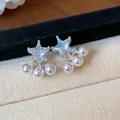 Macro detail of elegant star-shaped zircon stud earrings with hanging pearl accents - Light Blue Star Style