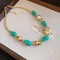 Primo piano di perline irregolari turchesi e dorate su una collana stile retrò - Blu