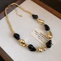 Primo piano di perline geometriche irregolari nere e oro su una collana in stile vintage - Nero