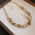 Primo piano di una collana in stile retrò con perle acriliche irregolari oro e ambra. - Grigio