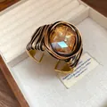 Primo piano del bracciale rigido bohémien in filo intrecciato con pietra di vetro ambrata - Pietra principale quadrata / Oro